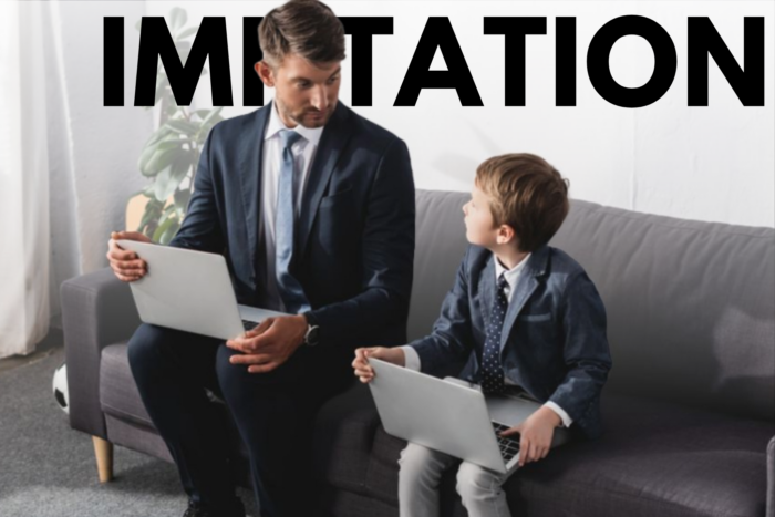 A man with a boy child with the word Imitation in the background.