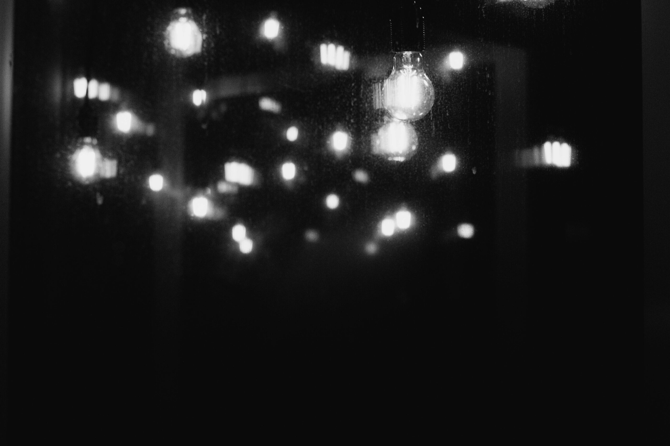 Artistic bokeh of light bulbs reflected on glass in monochrome representing Too Many Great Ideas